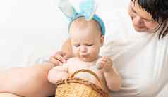 妈妈婴儿兔子耳朵复活节鸡蛋手坐着沙发父母孩子们玩在室内家庭庆祝复活节