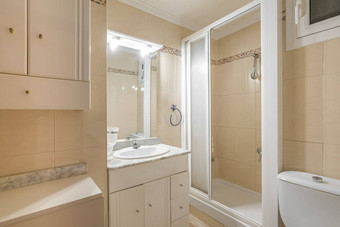 浴室明亮的灯小镜子光米色瓷砖墙开放淋浴小隔间白色塑料磨砂玻璃滑动通过沙拉酱表格抽屉白色水槽
