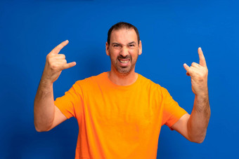 有胡子的拉丁美洲人男人。穿橙色t恤疯狂的表达式岩石象征手音乐明星重概念