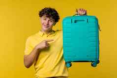 年轻的男人。随身携带的手提箱黄色的背景少年旅行蓝色的行李袋飞机手行李夏天旅行假期概念