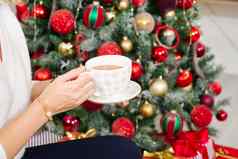 女孩白色毛衣持有杯温暖的咖啡茶背景圣诞节树