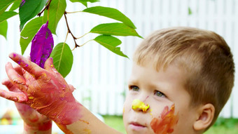 孩子四岁的男孩玩绘画手指油漆装修叶子树花园夏天