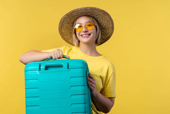 年轻的漂亮的女人随身携带的手提箱黄色的背景少年旅行蓝色的行李袋飞机手行李夏天旅行假期概念