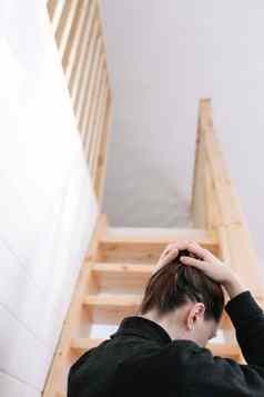 年轻的女人简单的发型回来视图木楼梯首页抑郁症孤独检疫概念精神健康护理住首页