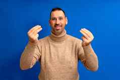 拉美裔男人。胡子站蓝色的孤立的背景意大利手势手手指自信表达式