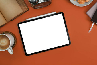 平躺数字平板电脑白色屏幕咖啡杯书橙色背景