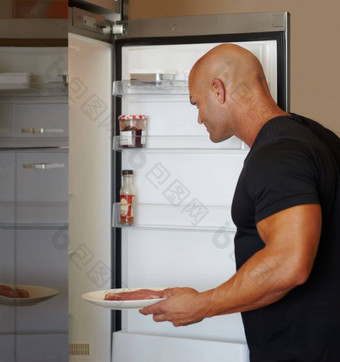 气质健康的餐肌肉发达的男人。放置板生肉冰箱
