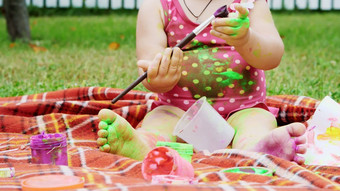 孩子一岁女孩玩绘画手指油漆装修花园坐着毯子床罩草草坪上夏天她是有趣的