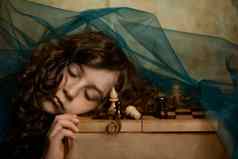 女孩黑暗卷曲的头发黑暗衣服下降了睡着了玩国际象棋棋盘梦想认为移动挑选国际象棋一块