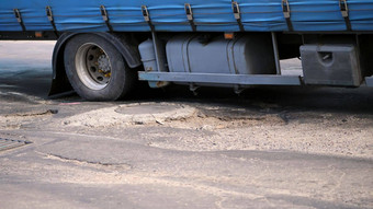 特写镜头可怜的路报道坑弯曲的沥青大卡车慢慢地通过拉伸路失修路修复