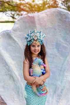 微笑女孩美人鱼服装大海贝持有色彩斑斓的海马玩具