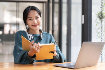 年轻的成人快乐微笑亚洲学生穿耳机会说话的在线闲谈，聊天会议移动PC大学校园虚拟办公室大学女学生学习远程