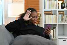 快乐的十几岁的女人休息舒适的沙发上聊天在线社会网络使视频调用聪明的电话