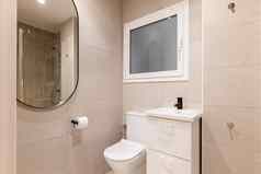 部分浴室厕所。。。碗脸盆表格美丽的椭圆形镜子墙排米色大理石瓷砖反射淋浴区域金属配件