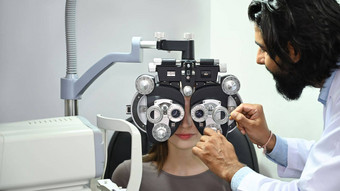 年轻的女病人检查眼睛愿景综合屈光检查仪视力测量测试机诊所