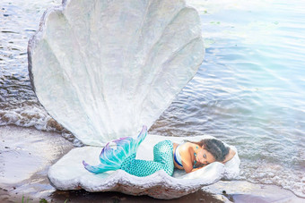 漂亮的女孩绿松石美人鱼服装睡觉大海壳牌