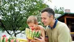 夏天花园父亲四岁的儿子减少西瓜吃有趣的男孩喜欢西瓜甜蜜的西瓜午餐家庭