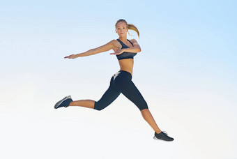 <strong>飞跃</strong>健身完整的长度拍摄运动年轻的女人跳蓝色的天空