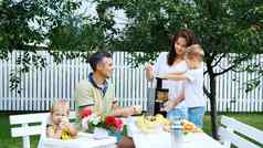 快乐美丽的家庭妈妈爸爸年儿子一岁女儿使新鲜的水果汁夏天花园家庭花休闲时间