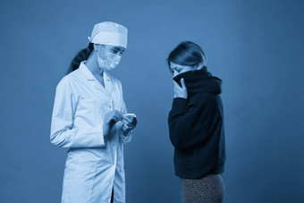 年轻的医生测量温度病人温度计工作室拍摄蓝色的背景