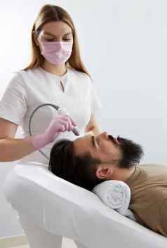 医生女皮肤科医生毛发学家使过程刺激头发增长头病人男人。