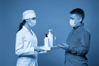 医生应用抗菌喷雾病人手蓝色的背景