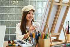 微笑女画家坐着前面帆布绘画图片水彩休闲活动概念