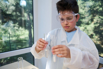 青少年小学生穿白色实验室外套持有测试管化学物质化学实验室孩子们科学概念