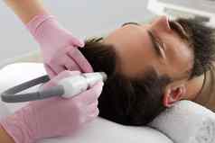 医生女皮肤科医生毛发学家使过程刺激头发增长头病人男人。