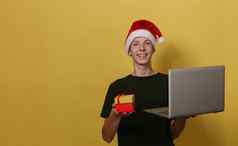 有吸引力的一年男孩圣诞老人他持有灰色的移动PC红色的礼物盒子
