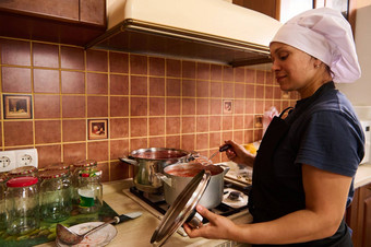 女人家庭主妇激起沸腾番茄汁锅厨房勺子使番茄酱汁罐头蔬菜