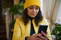 非洲美国女人明亮的黄色的夹克他电话检查新闻饲料放松咖啡商店
