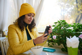 美丽的非洲美国女人放松咖啡房子智能手机检查社会网络发布内容