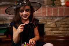 女孩女巫狂欢节服装治疗坐着壁炉覆盖蜘蛛网络快乐万圣节