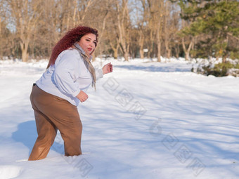 脂肪红发女人白色运动衫走雪地里