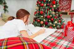 快乐十几岁的女孩笔笔记本使列表列表一年床上圣诞节树圣诞节假期概念