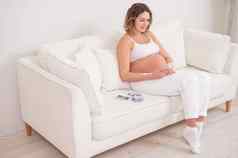 怀孕了女人坐在白色沙发持有智能手机胎儿超声波筛选