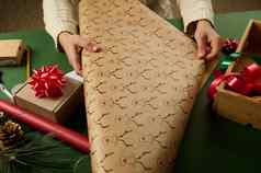 特写镜头女人卷包装礼物纸鹿模式包装圣诞节礼物一年圣诞节准备工作