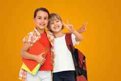 照片小女孩小学生妹妹同学们持有书孤立的橙色颜色背景