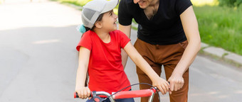 快乐家庭<strong>父亲教孩子</strong>女儿骑自行车公园自然
