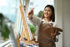 快乐的年轻的女人享受有创意的休闲活动绘画图片明亮的现代艺术工作室