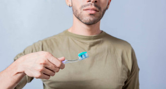 人显示牙刷牙膏年轻的男人。显示牙刷牙膏孤立的的家伙持有刷牙膏白色背景