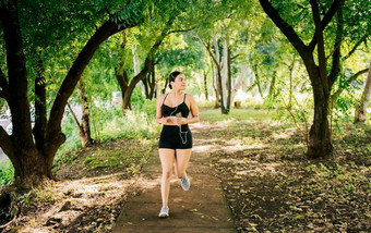 生活方式运动年轻的女人运行公园包围树健康的生活方式概念运动年轻的女人运行公园女孩运行公园听音乐