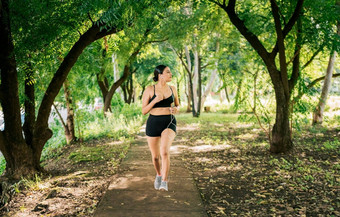 健康的生活方式概念女人慢跑绿色公园运动年轻的女人运行公园女孩运行公园听音乐生活方式运动女人运行公园