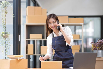 年轻的亚洲女人工作首页年轻的老板女人会说话的客户工作快乐情感人在线购物锻造企业家自由工作概念