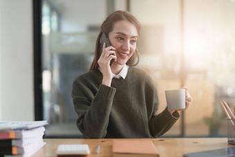 美丽的亚洲业务女人会说话的移动电话工作的地方办公室女人会说话的电话客户端业务金融会计概念