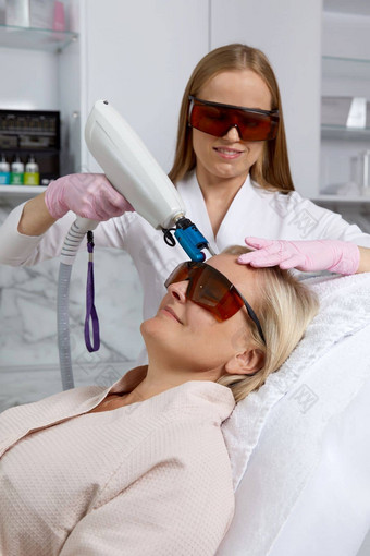 中间岁的女人接收激光治疗美容诊所穿保护眼镜