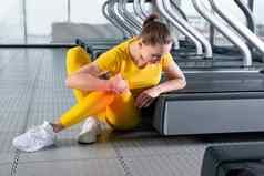 年轻的女人运动服装疼痛膝盖培训健身房女孩坐着地板上触碰膝盖疼痛