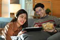 放松年轻的夫妇看电影数字平板电脑吃爆米花娱乐休闲活动概念