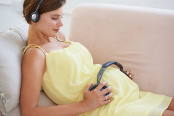 旋律平静婴儿怀孕了女人把耳机胃玩婴儿舒缓的音乐